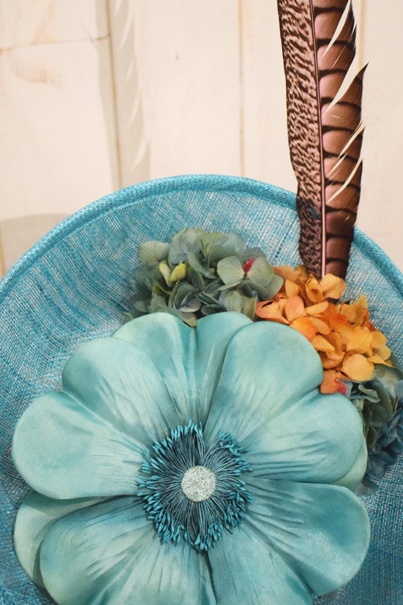 tocado de sinamay azul claro con flor grande y pluma faisan para invitadas fiesta eventos de apparentia